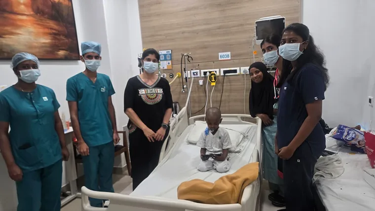 Dr. Neema Bhat with the nursing and care team beside a young patient in a hospital room